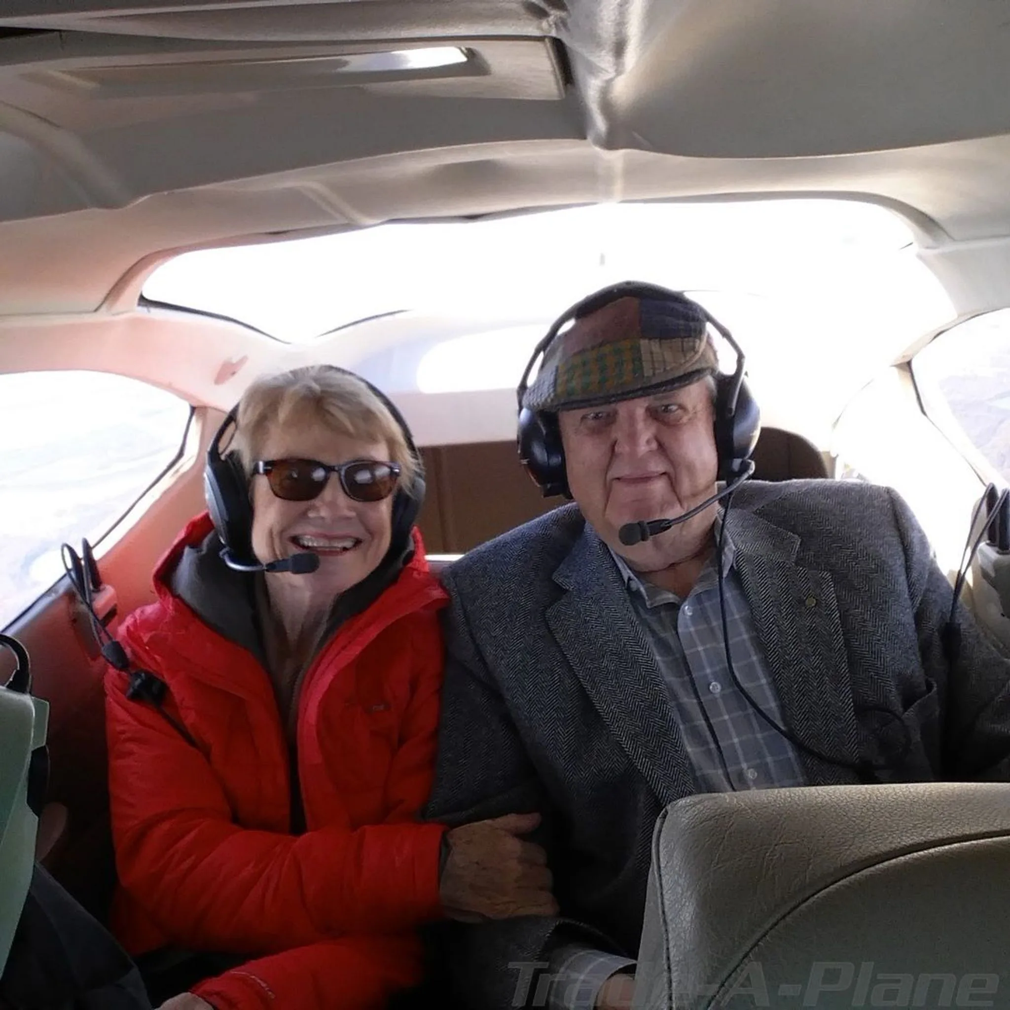 Two passengers wearing headsets are seated in the aircraft cabin.