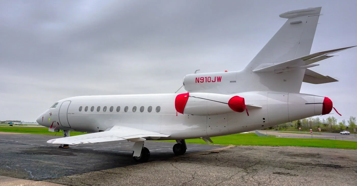 A white Dassault Falcon 900 is parked on the tarmac.