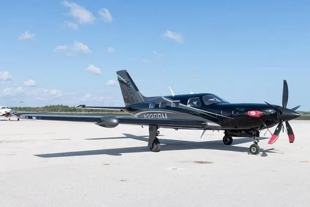 A black Piper M600 aircraft with white and grey accents, registration N230PM, parked on a tarmac under a clear sky.