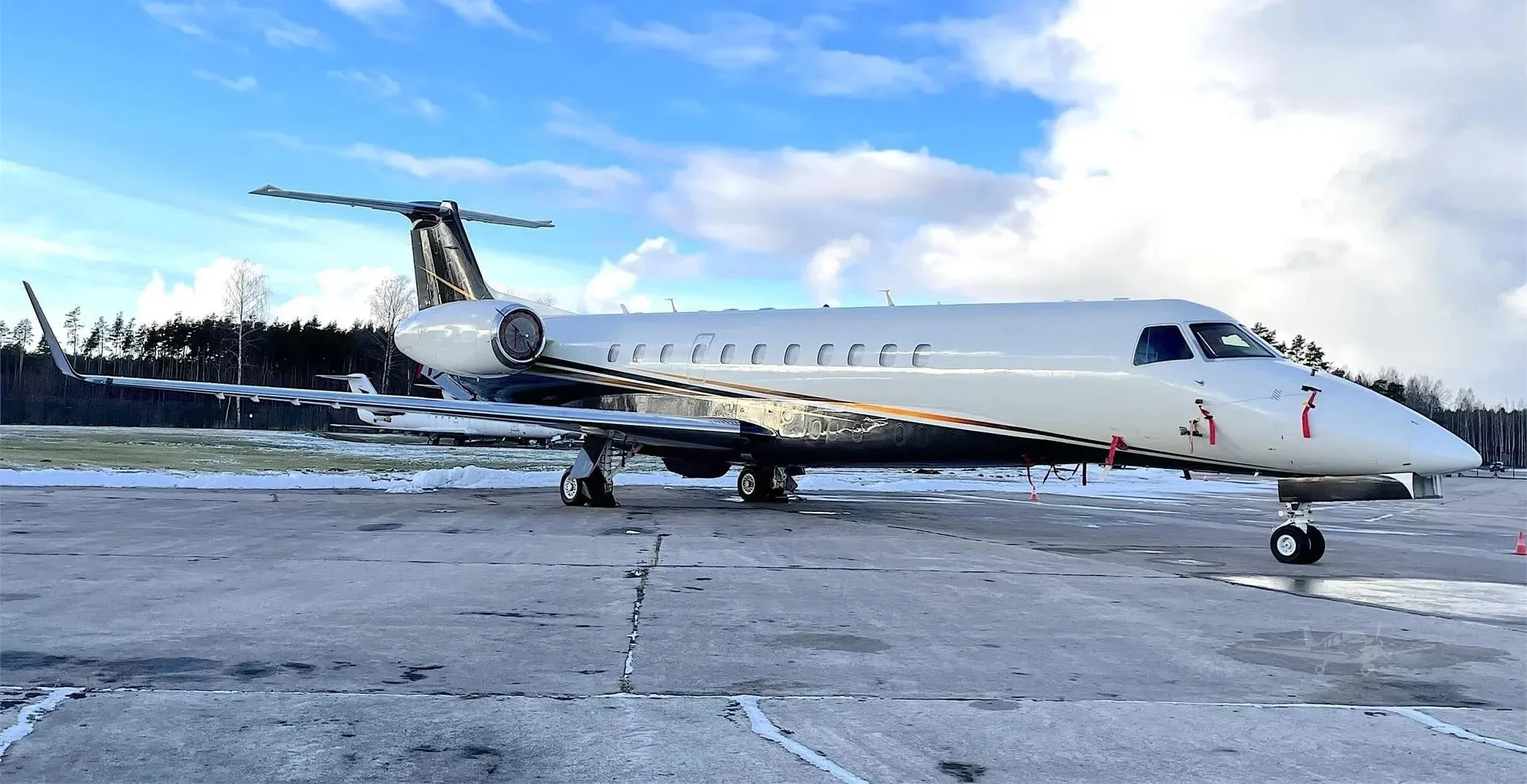 An Embraer Legacy business jet parked on a concrete airfield.