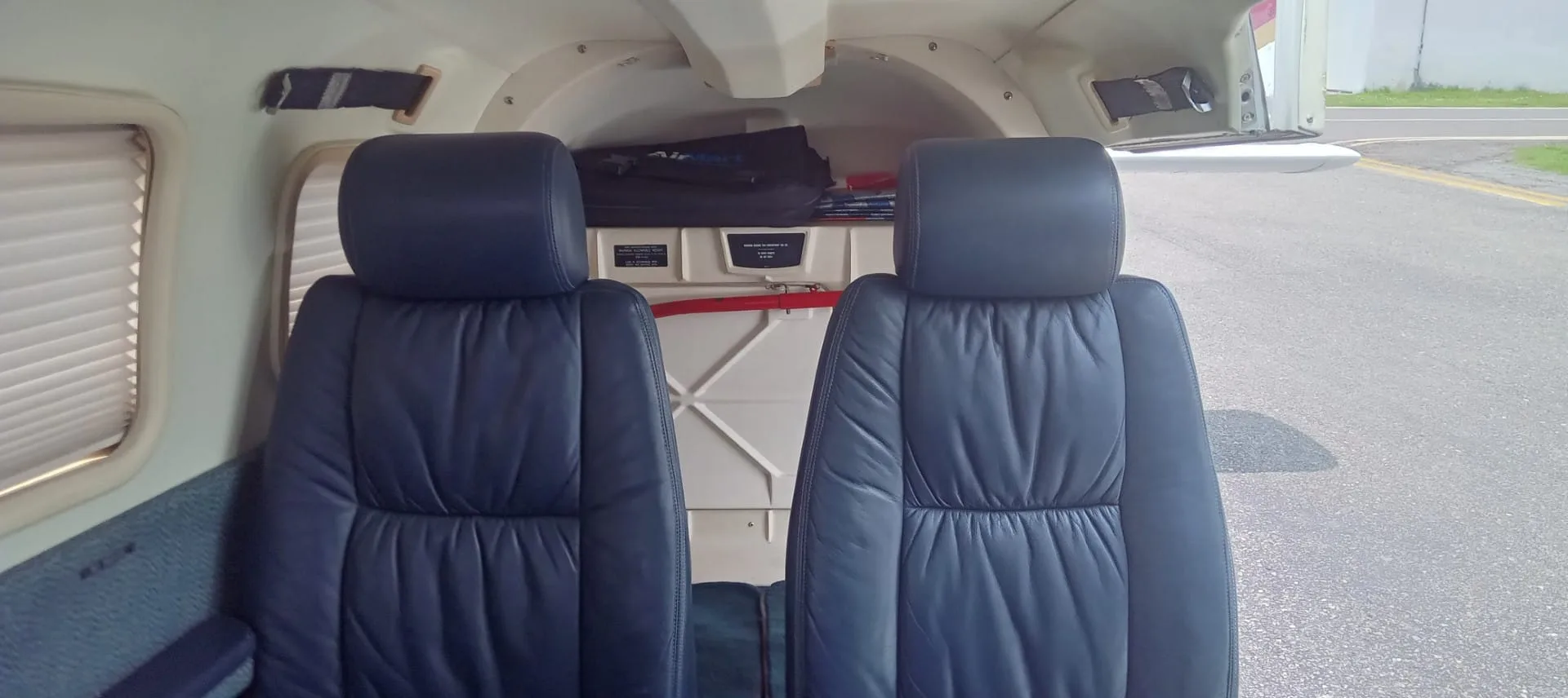 Two dark blue leather passenger seats in the rear cabin of a small aircraft.