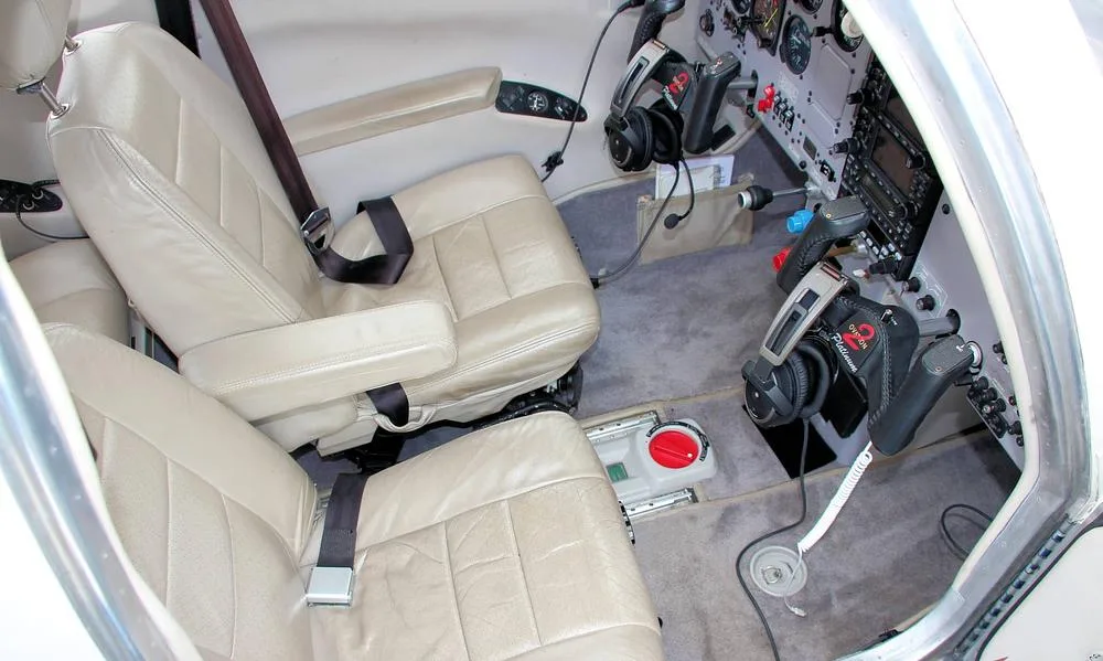 The light tan leather front seats of the aircraft cabin, with part of the cockpit visible on the right.