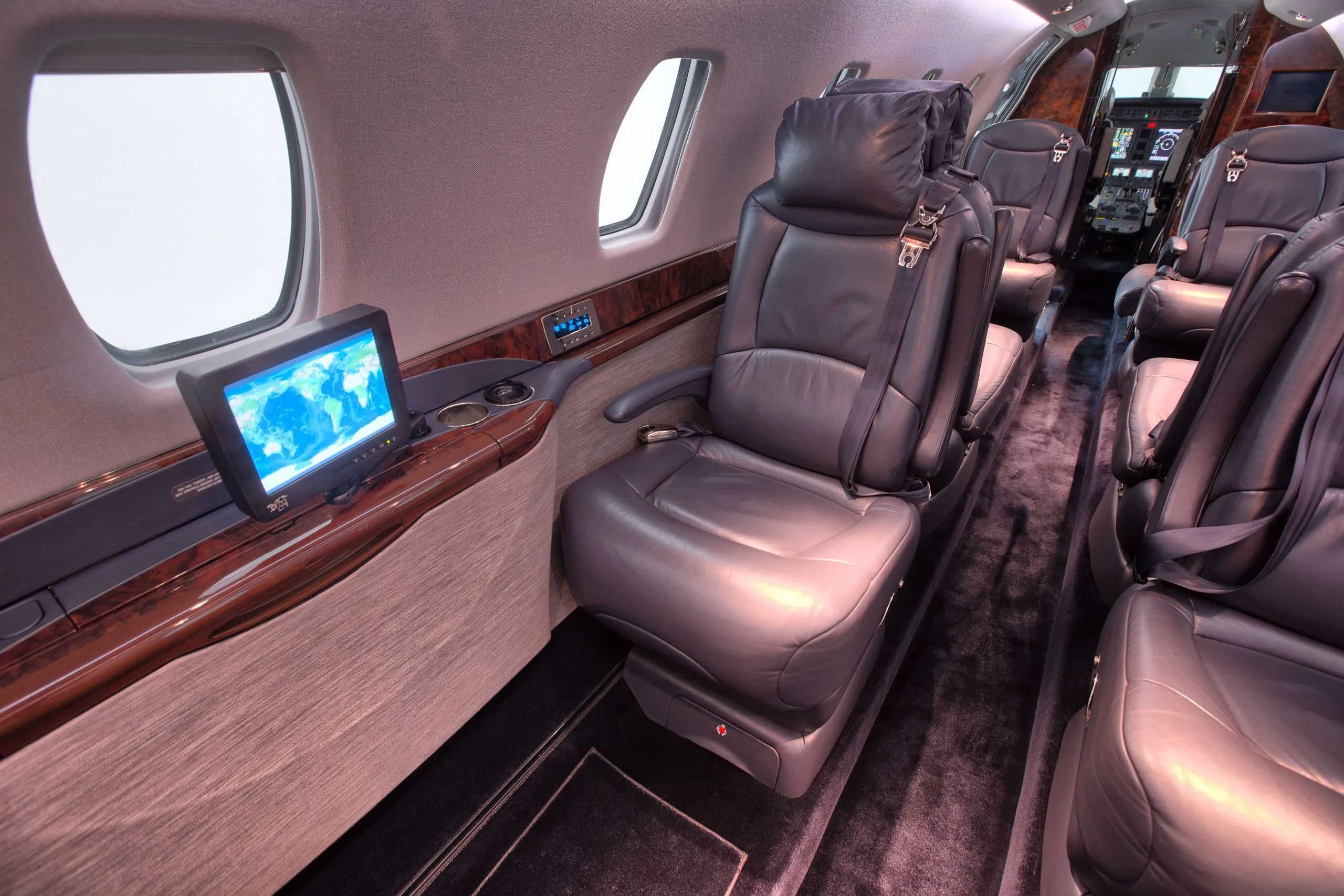 A view of the aircraft cabin with leather seats and a monitor.