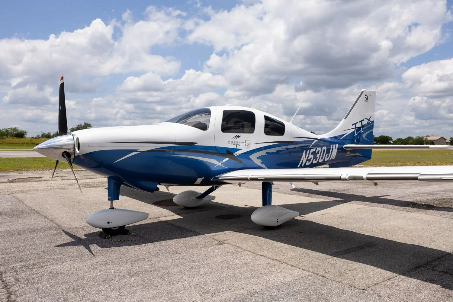 A three-quarter front view of the white and blue Cessna TTX N530JM parked on a tarmac.