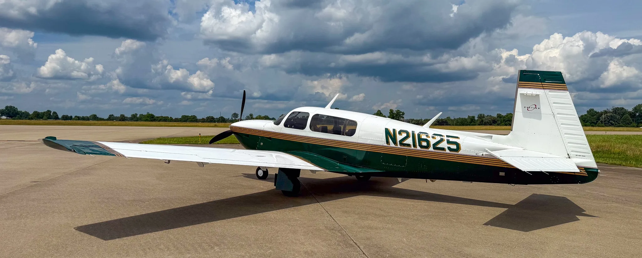 A side view of the white and green Mooney M20 aircraft with registration N21625 on an airfield.