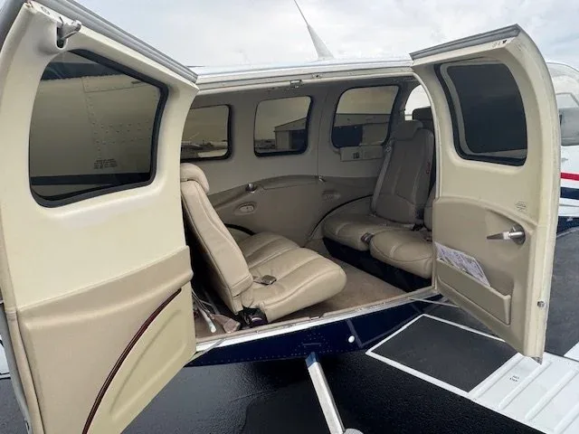 View of the aircraft interior with tan leather seats and open doors.
