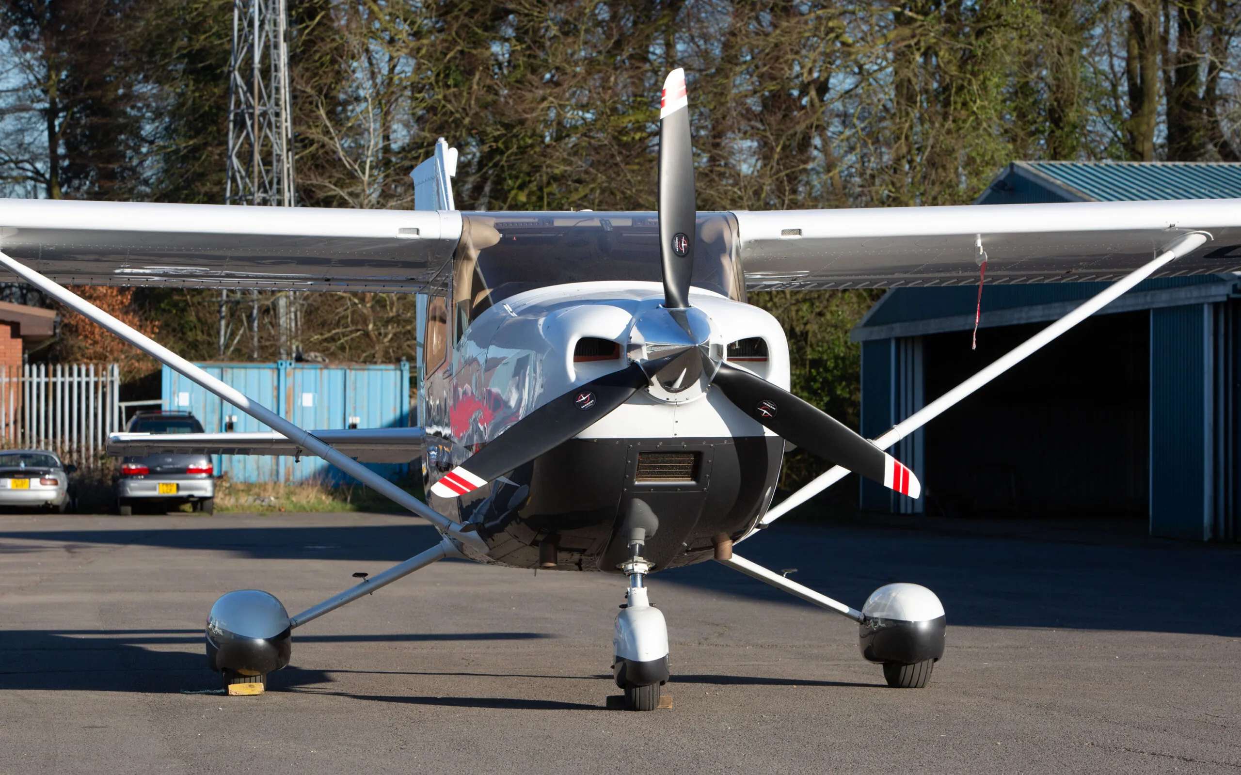 Front view of a white and black Cessna 182T (G-CYRL) parked on an airfield.