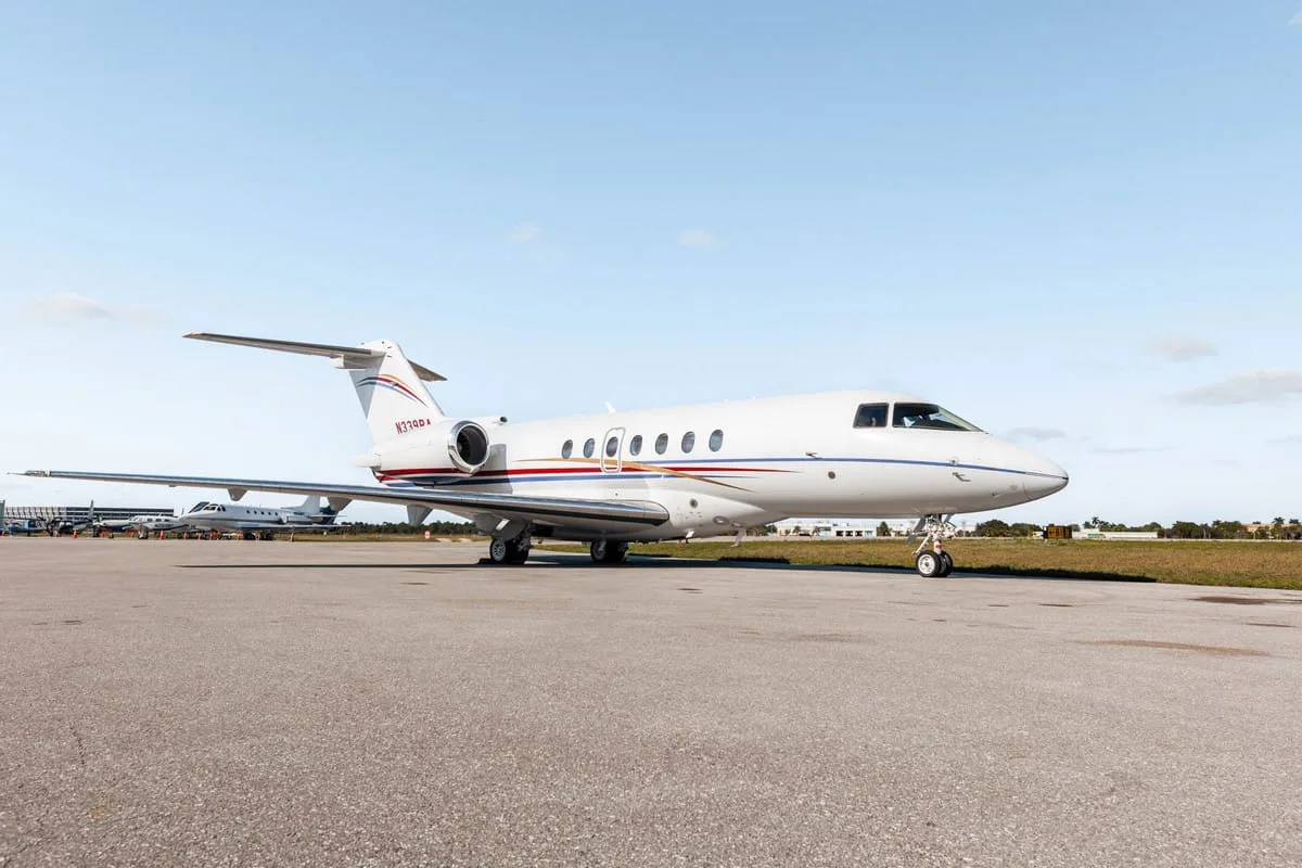 A white Hawker 800XP business jet with red and blue stripes, registration N339RA, parked on the tarmac from a front-side view.