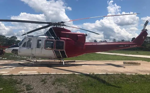 A side view of a red, white, and black Bell 412 helicopter parked on a helipad.