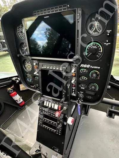 The cockpit instrument panel of a Robinson R66 Turbine helicopter with a large Garmin display and various gauges.