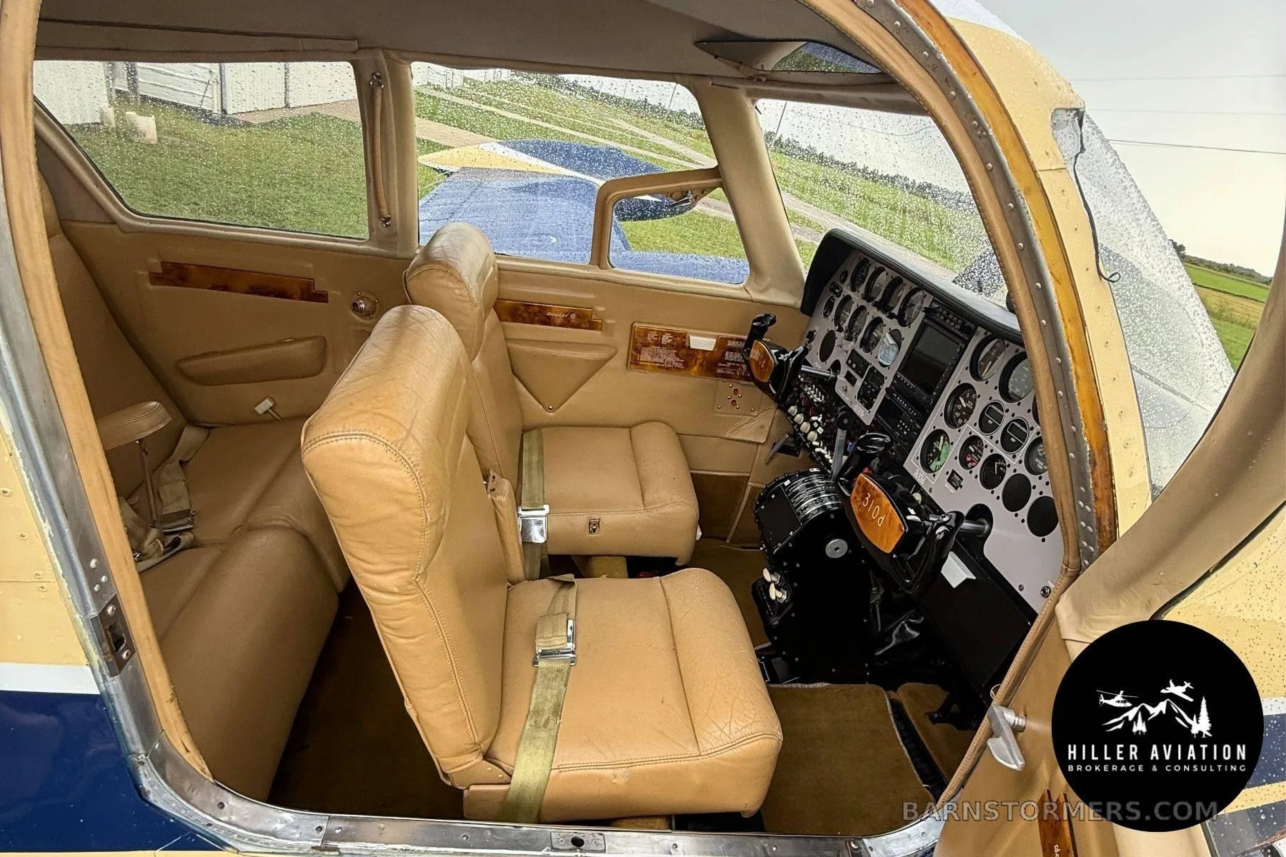 The tan leather interior of an aircraft cabin, showing front seats and the instrument panel.