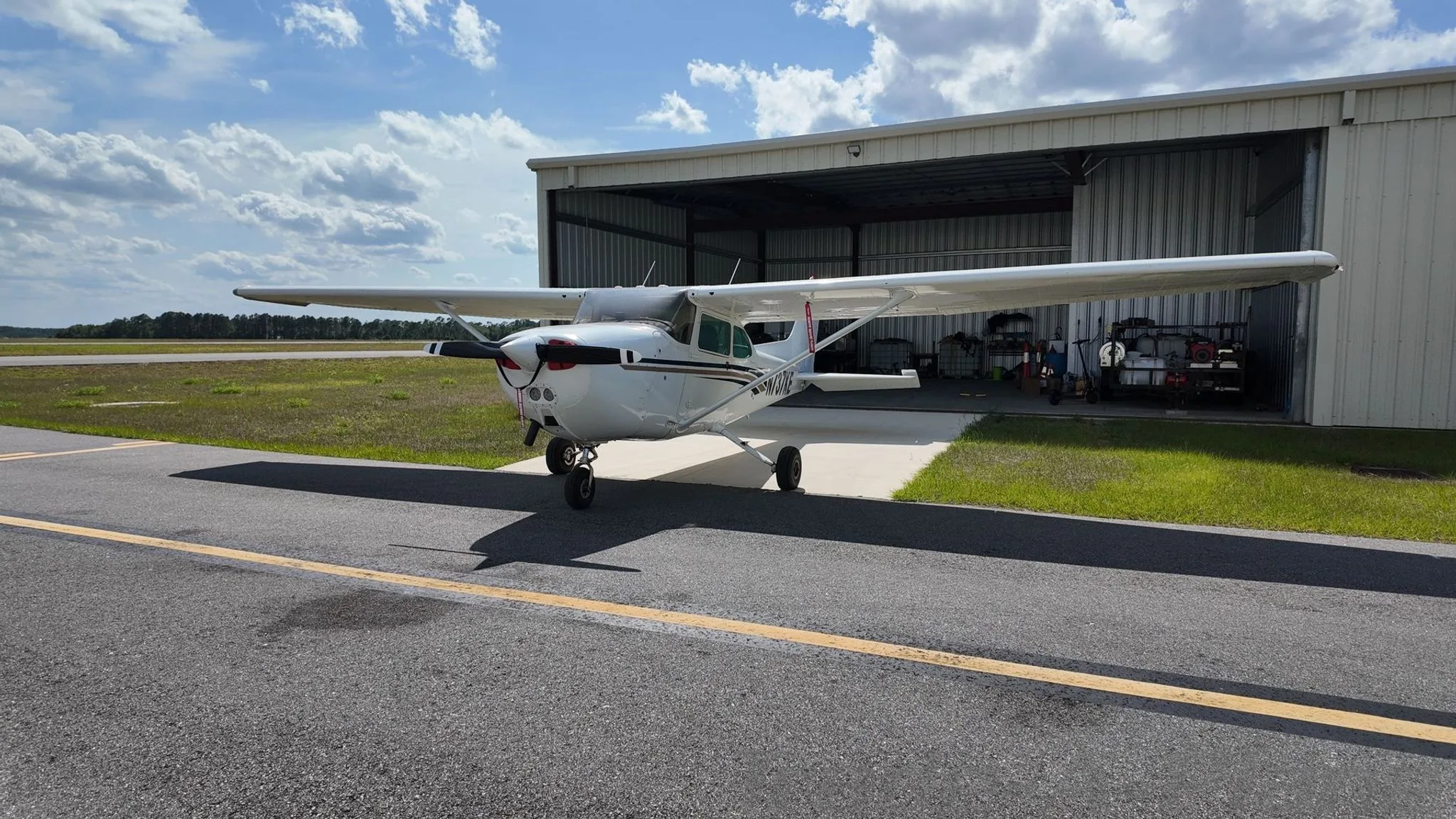 A front-quarter view of a white Cessna 172 Skyhawk with brown and blue stripes, tail number N737KE, parked on an airfield.