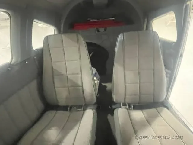 The rear cabin interior of a small aircraft, showing two grey upholstered seats.