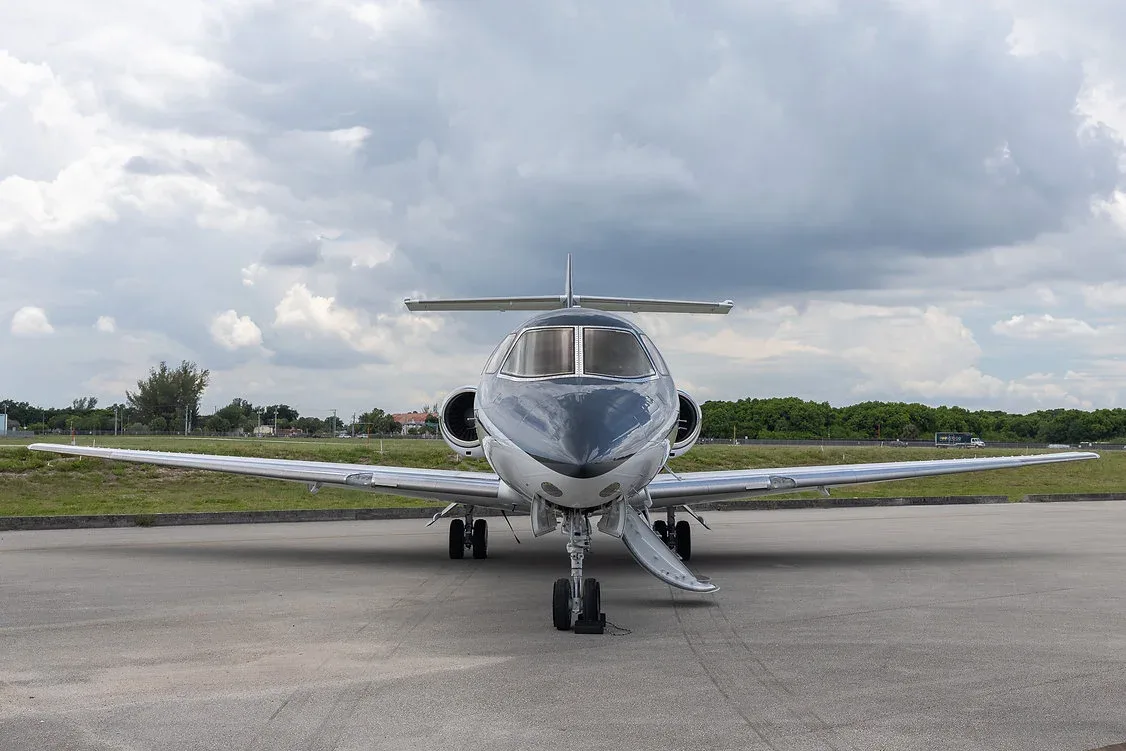A head-on view of a white and black business jet, registration N432SM, parked on an airfield.