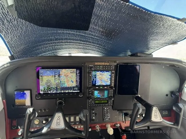 The cockpit of a small aircraft with modern glass panel displays and a sunshade.