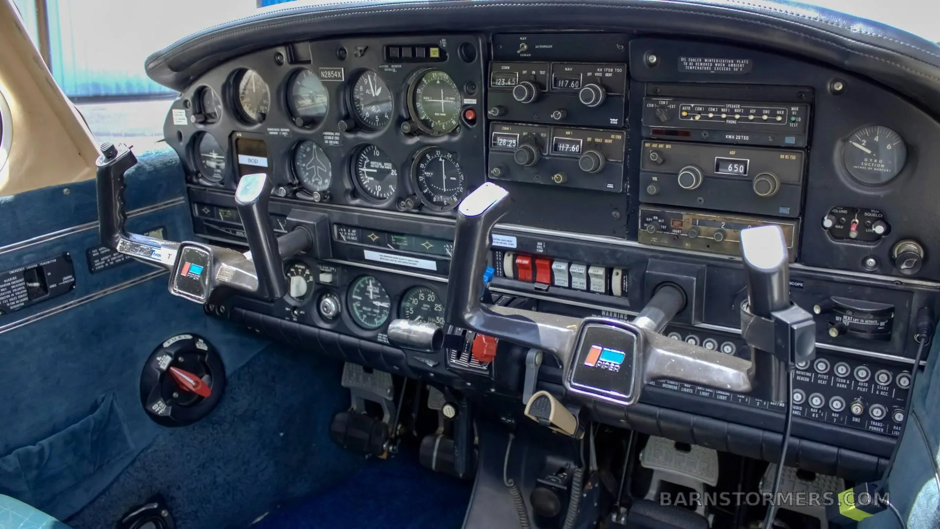 The cockpit of a light aircraft, showing the instrument panel with various gauges, radios, and two control yokes.