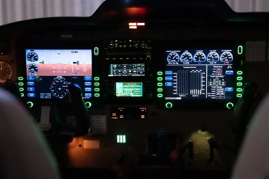 An illuminated aircraft cockpit with multiple digital displays showing flight and engine information.