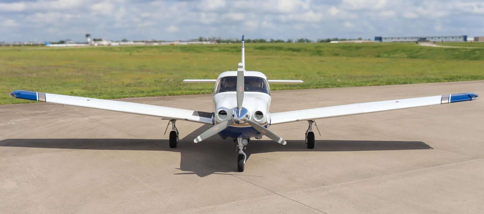 A head-on view of the Piper Saratoga II HP aircraft, N954K, with its propeller centered on an airfield.