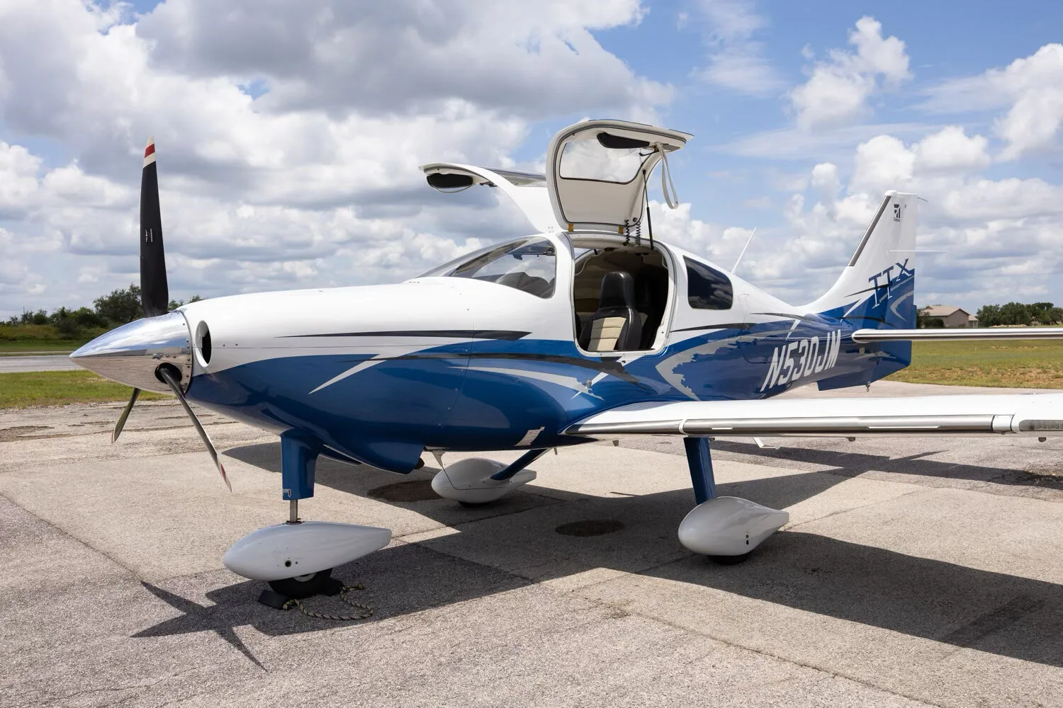 A three-quarter front view of the Cessna TTX N530JM with its gull-wing doors open, parked on a tarmac.
