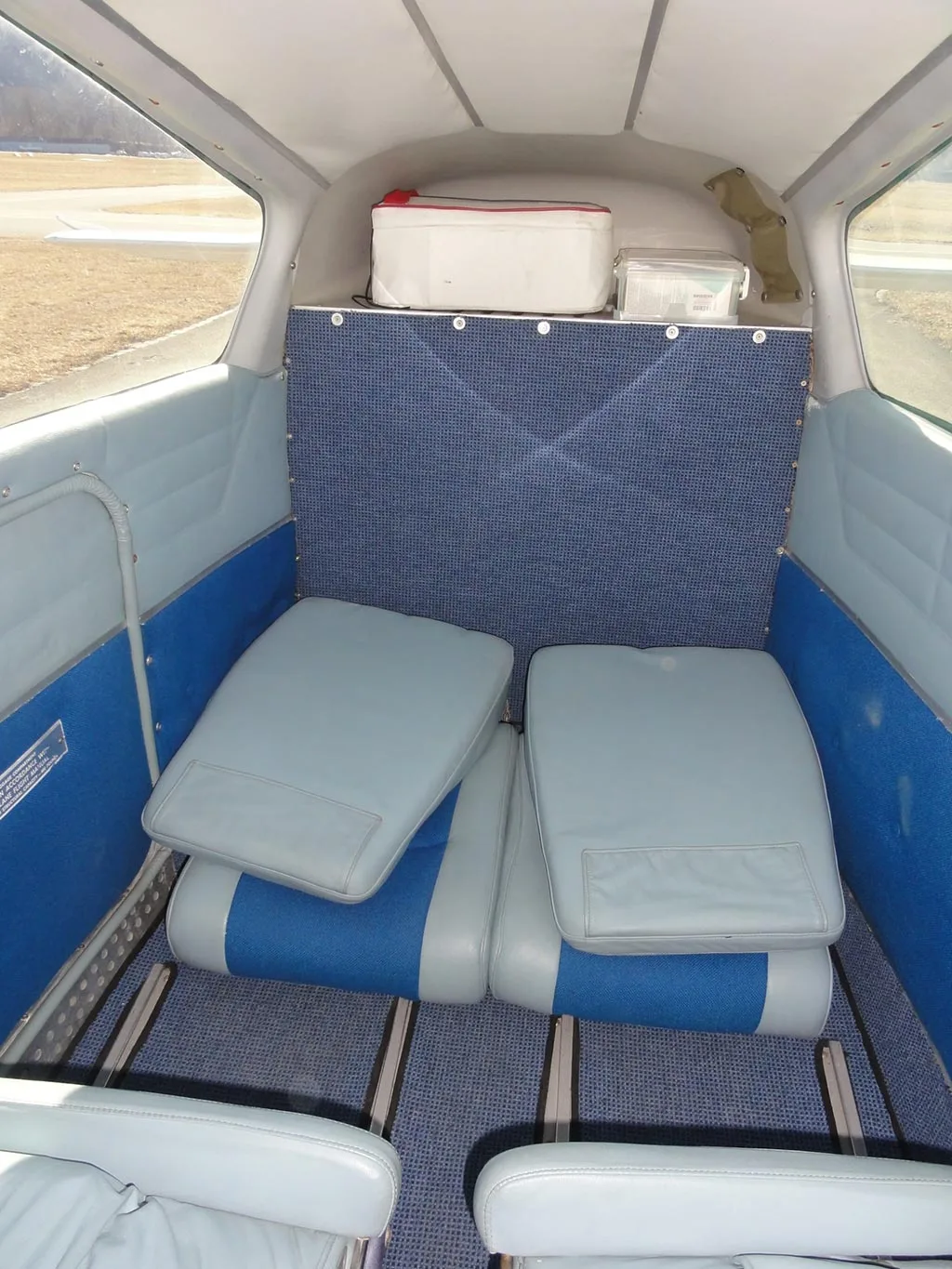 The aircraft's rear cabin with blue and light grey seat cushions removed and stacked on the seat bases.