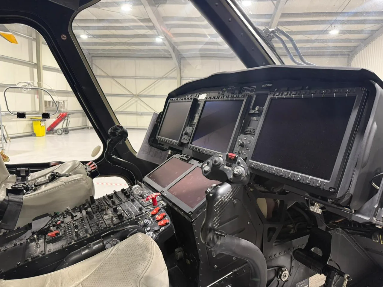 Cockpit view of the A6-FHG helicopter with multiple display screens.