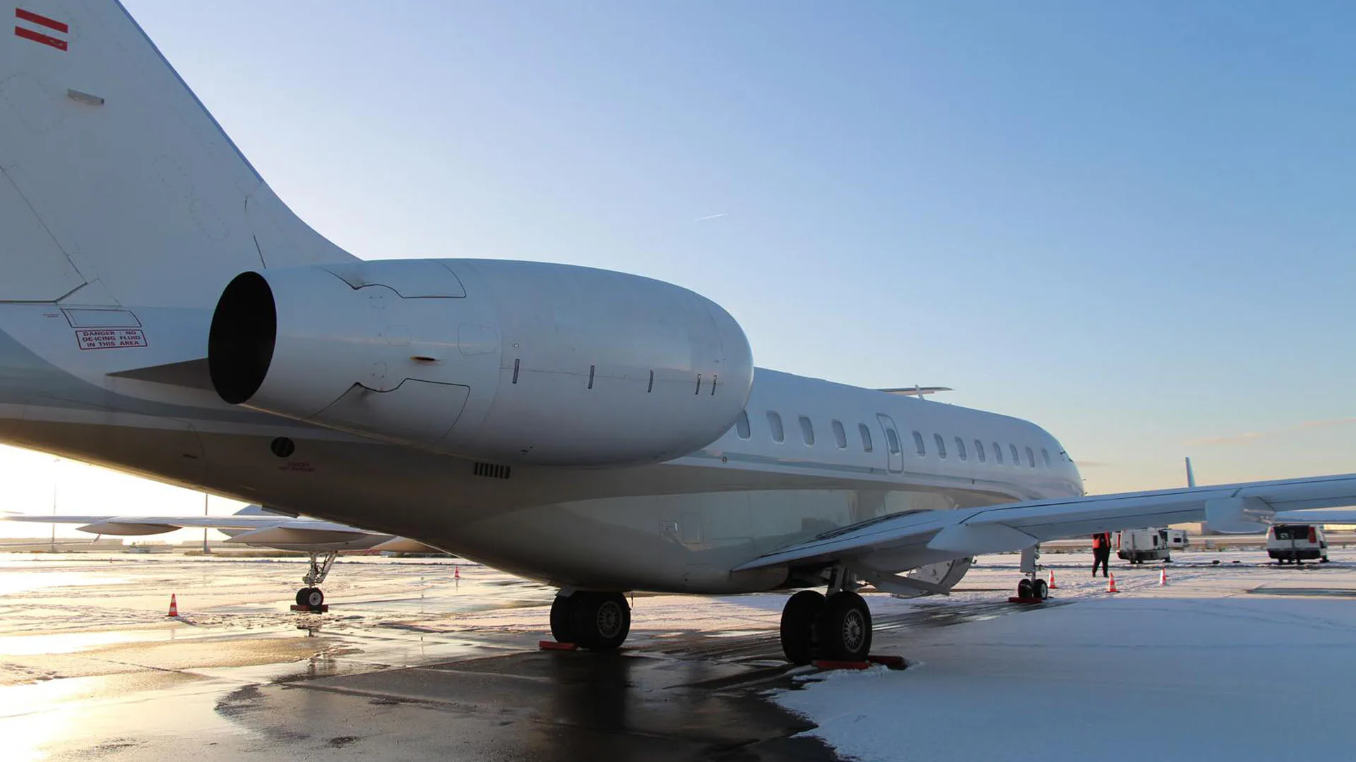 A white jet aircraft is parked on a snowy tarmac.
