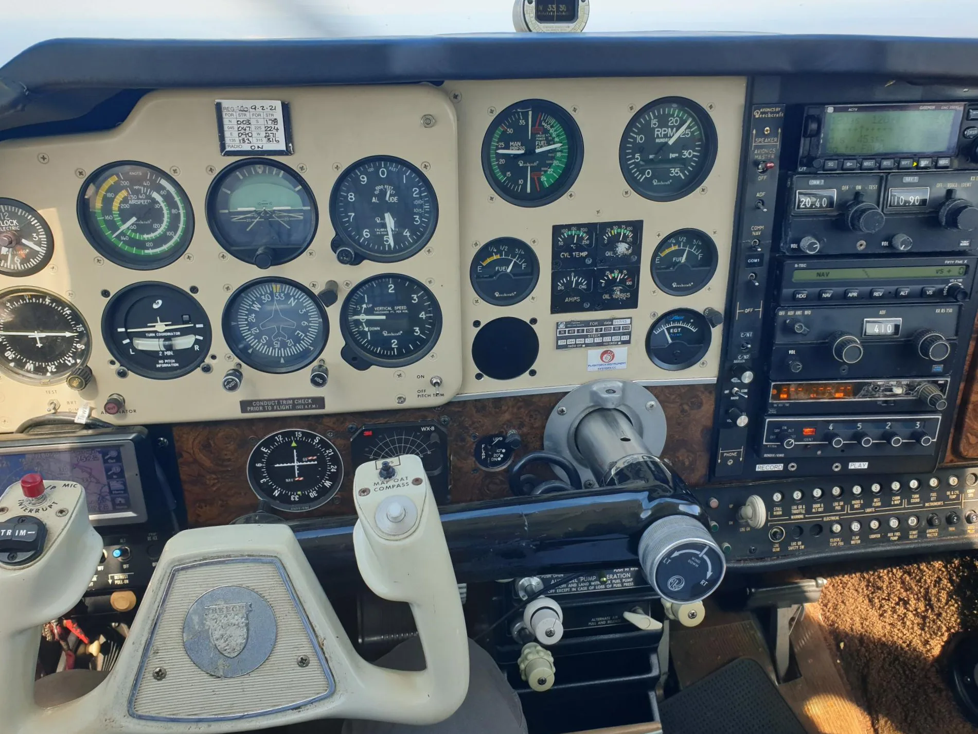 The cockpit of a light aircraft, featuring an instrument panel with analog gauges, avionics, and a white control yoke.