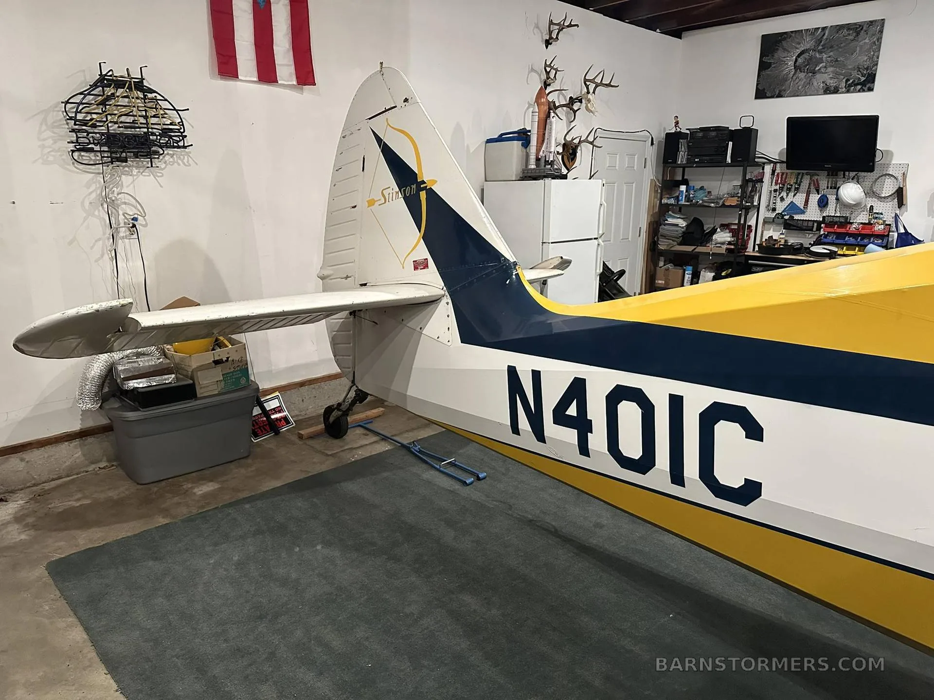 The tail section of the yellow and blue Stinson aircraft, N401C, with 'Stinson' logo on the fin.