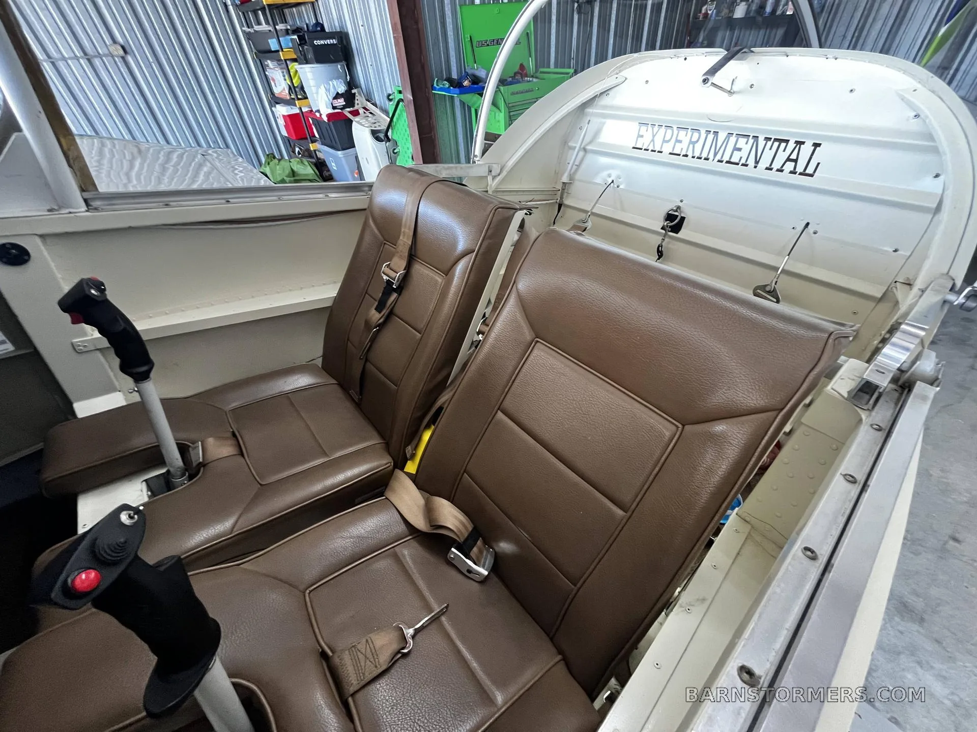 The two brown leather seats of the N49BW experimental aircraft's cabin, with control sticks visible.