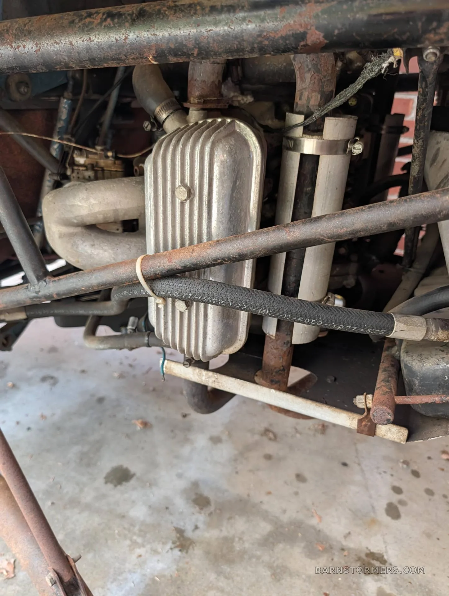 A close-up view of the exposed engine and mechanical components of an experimental helicopter, showing pipes and a silver valve cover.