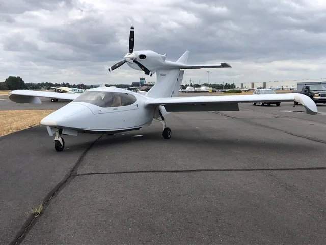 A white Searey amphibian aircraft, N9004T, is parked on an asphalt runway, viewed from the front-left.