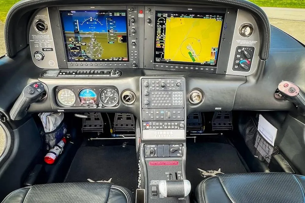 The modern glass cockpit of a Cirrus SR22 aircraft, featuring dual large display screens and a central control panel.