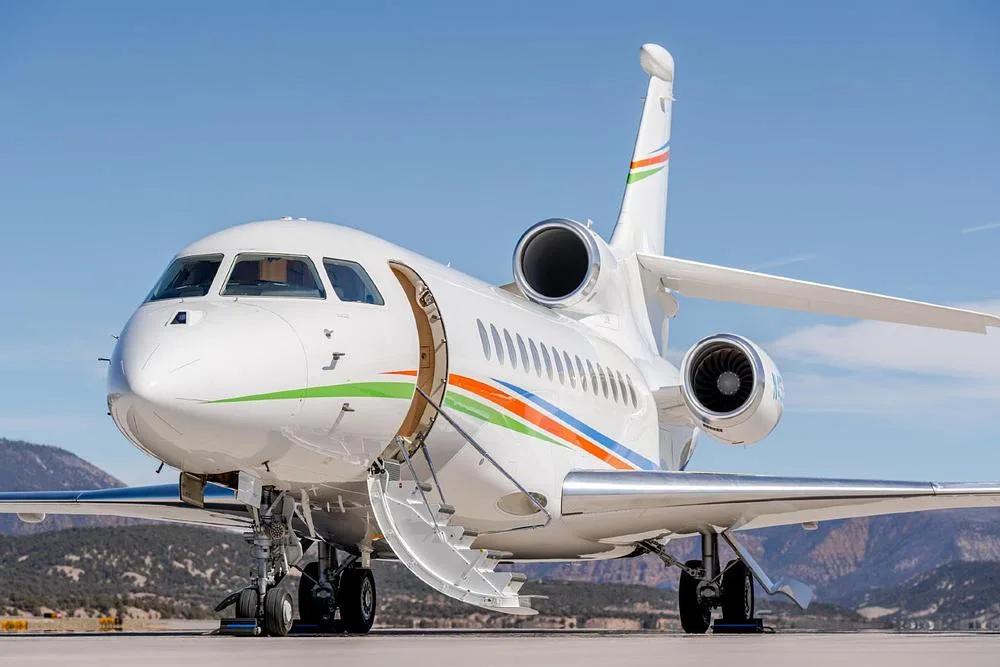 The white Dassault Falcon 900EX, registration N496AC, with its main cabin door open and airstairs extended, parked on an airfield.