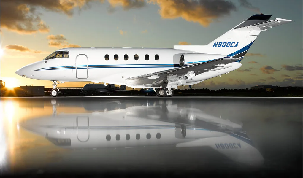 A white business jet with blue and black accents, registration N800CA, parked on a tarmac at sunset with a reflective surface.