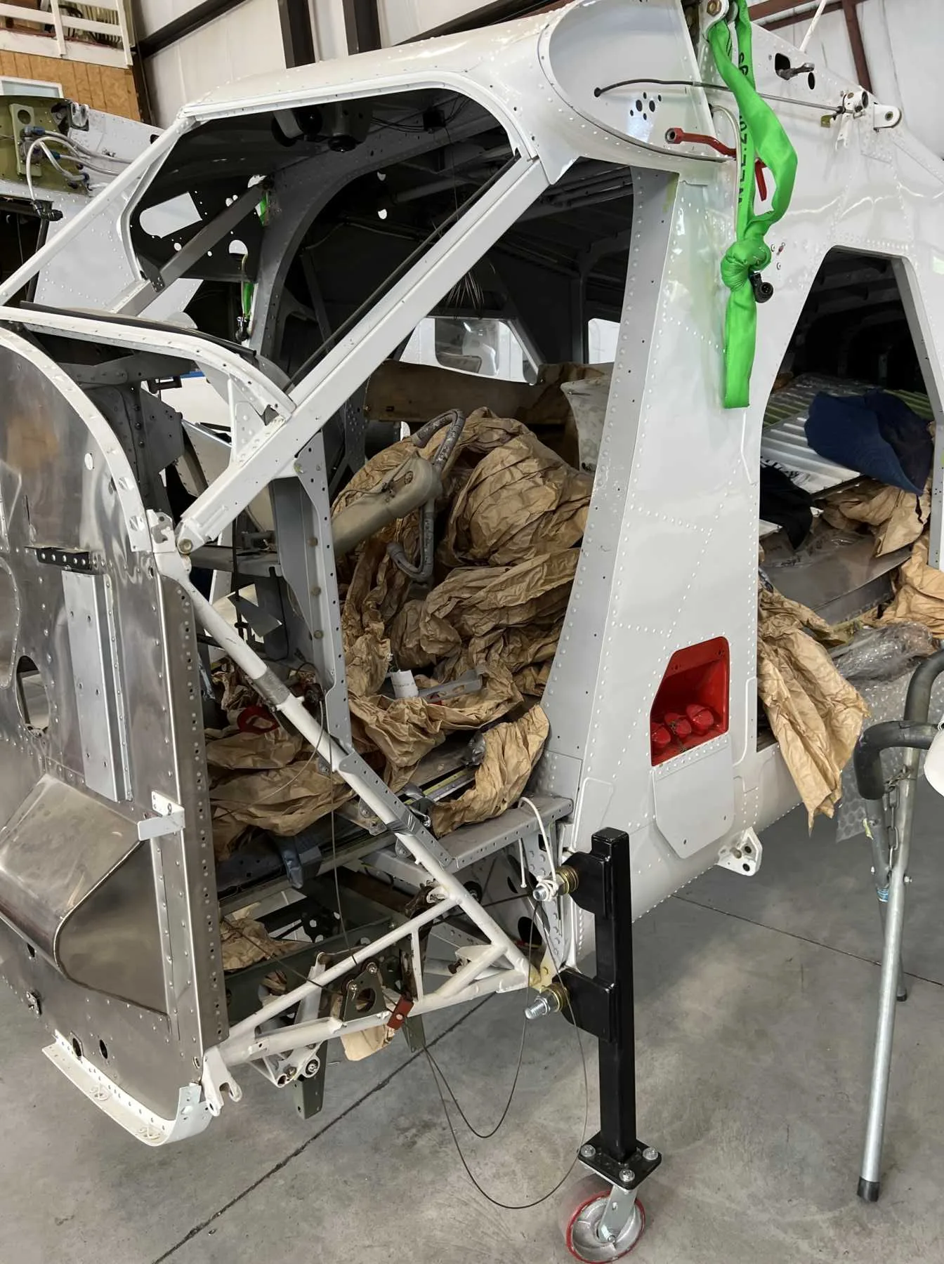 The white fuselage of an aircraft with its interior filled with brown packing paper, in a hangar.