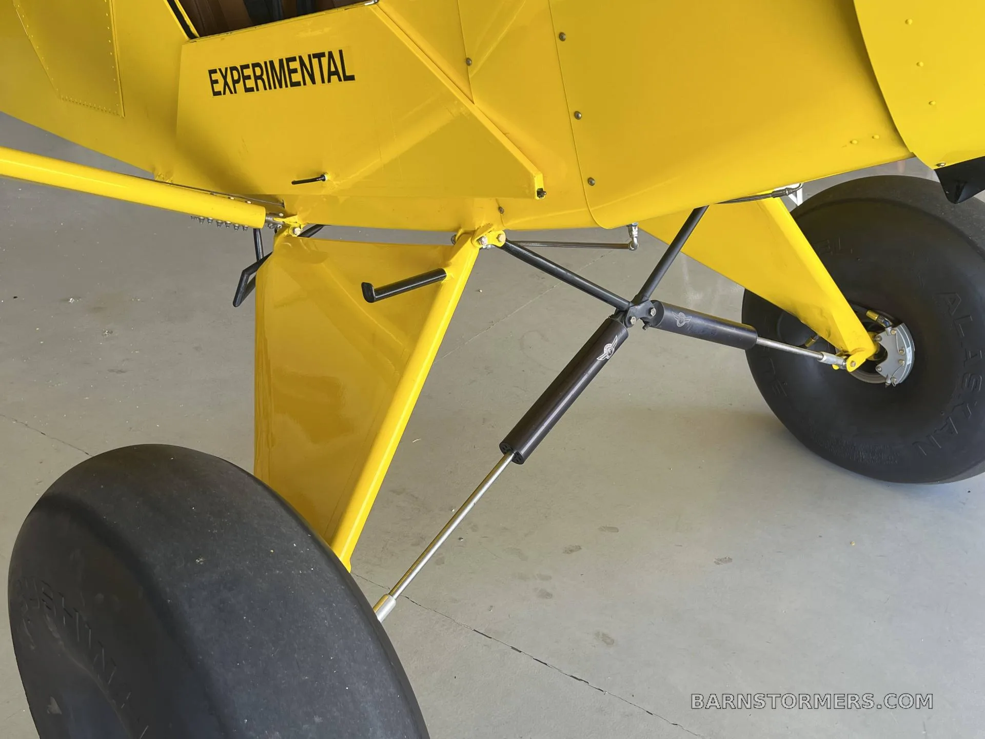 Close-up view of the large tires and landing gear struts of a yellow experimental aircraft.
