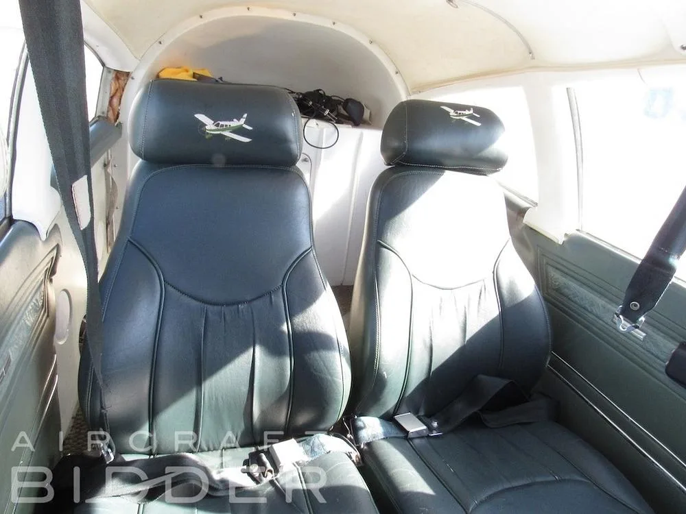 Two dark green leather front cabin seats with aircraft logos on the headrests inside the aircraft.
