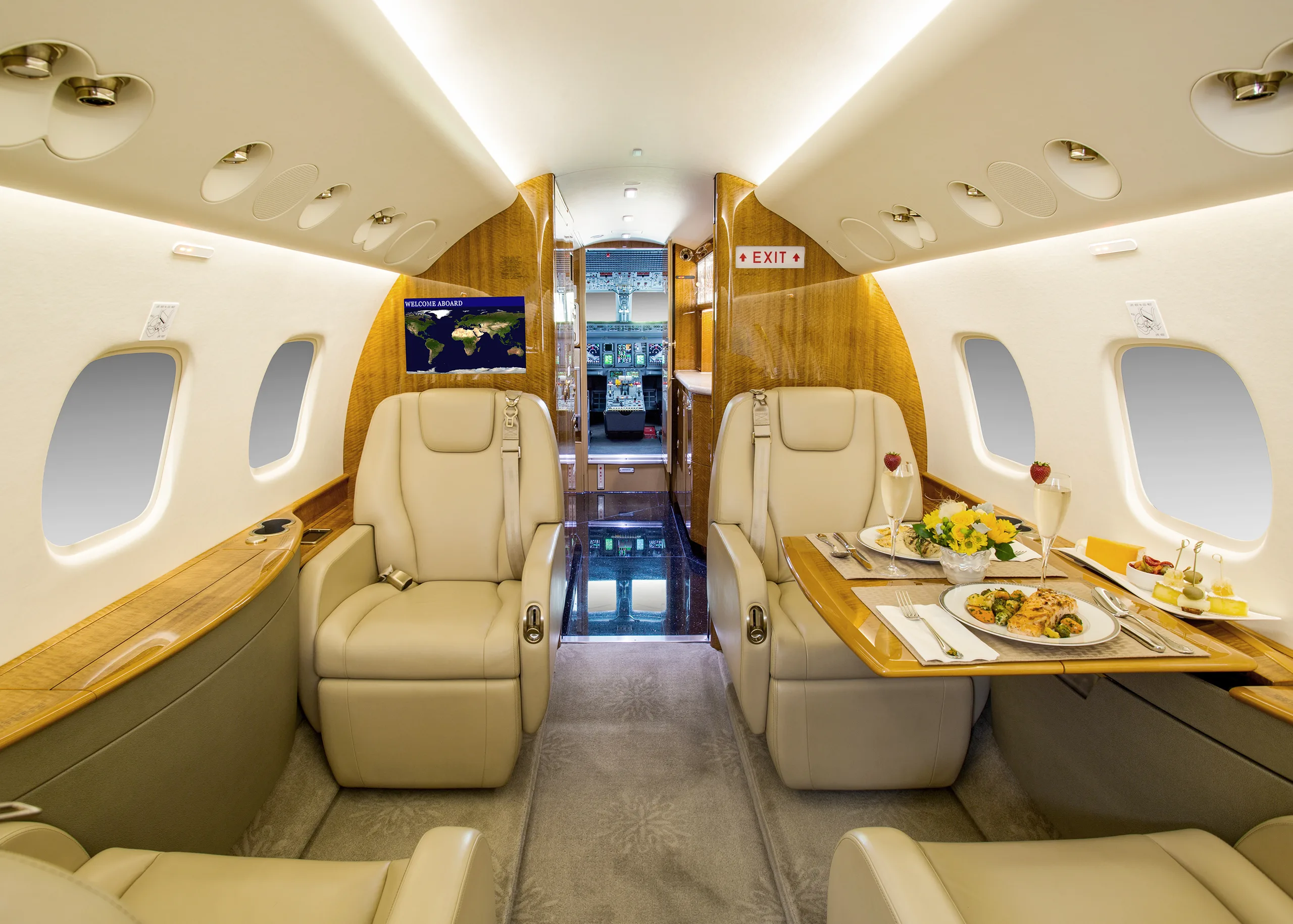 The luxurious interior of a private jet cabin with beige seats, a dining table set for two, and a view into the cockpit.
