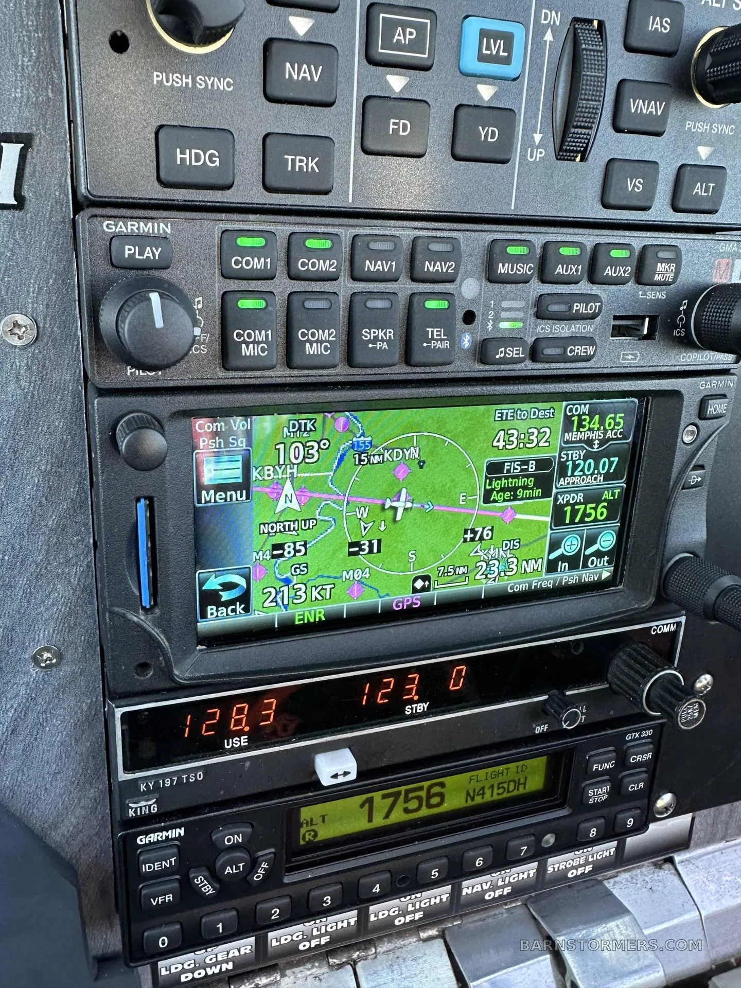 A close-up view of the Garmin avionics stack in the cockpit, displaying navigation and communication frequencies.