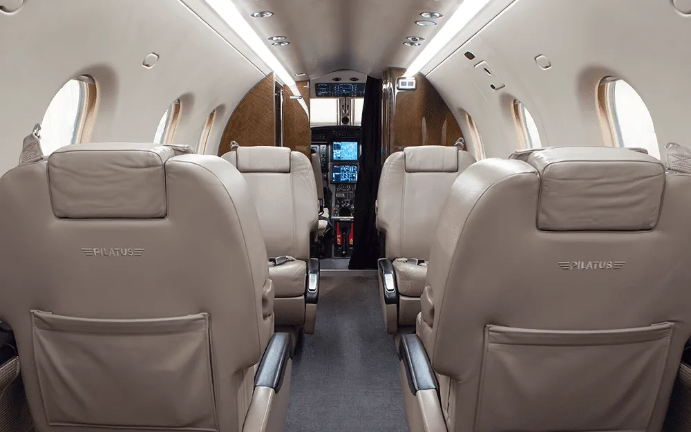 The beige leather interior cabin of a Pilatus PC-12 NG, looking forward towards the cockpit.