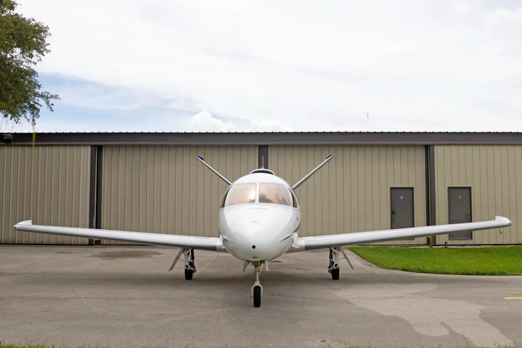 A head-on view of the white Cirrus Vision Jet (N696MR) parked on a tarmac in front of a hangar.