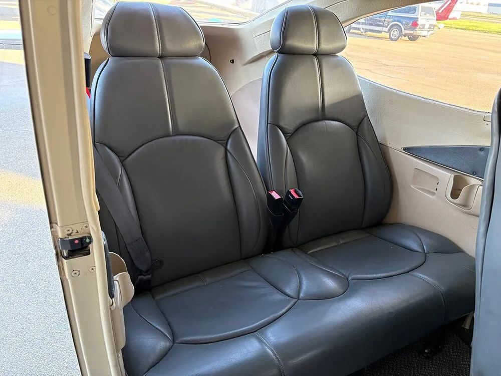 View of the gray leather rear passenger seats inside the aircraft cabin.
