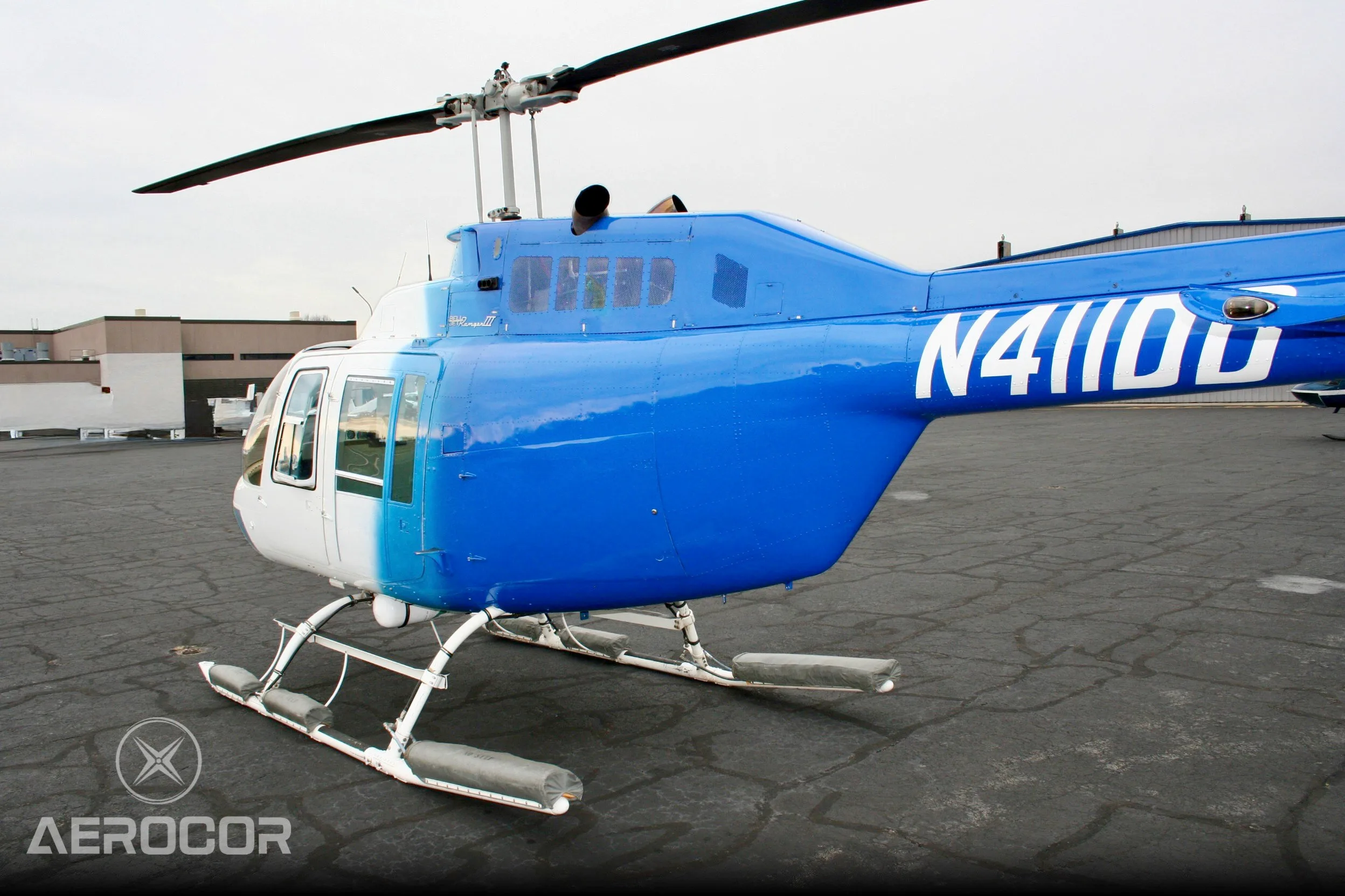 A close-up side view of the blue and white Bell JetRanger III helicopter, tail number N411DD, showing the cabin and tail boom.