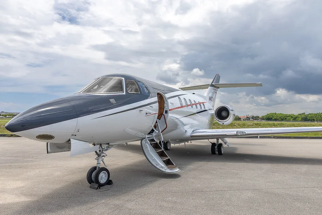 A white and black business jet, registration N432SM, with its passenger door open and stairs extended, parked on an airfield.