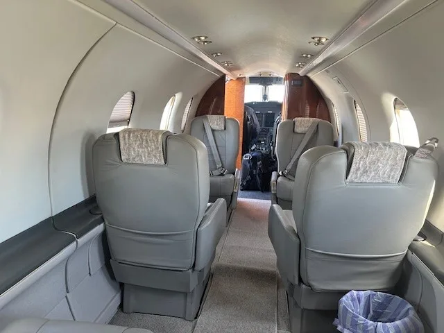 The interior cabin of an aircraft showing grey leather seats and a view towards the cockpit.