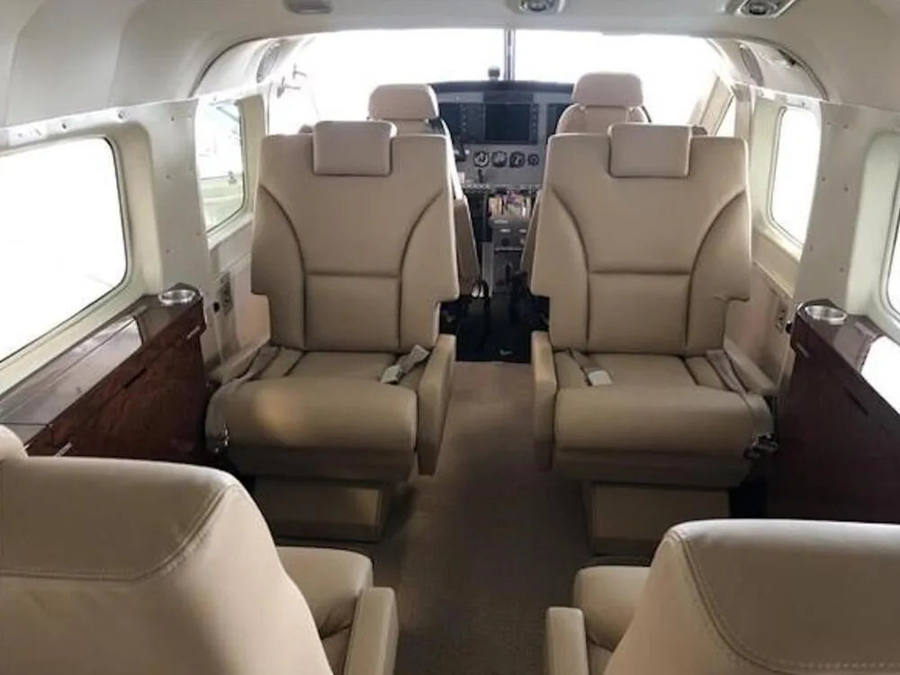 View from the rear of the cabin showing tan leather passenger seats and the cockpit beyond.