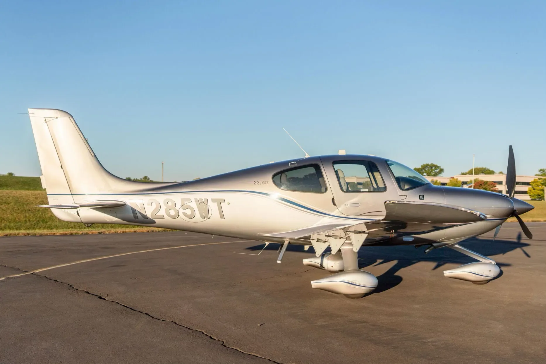A silver and grey Cirrus SR22 aircraft (N285WT) with blue accent stripes parked on an asphalt tarmac.
