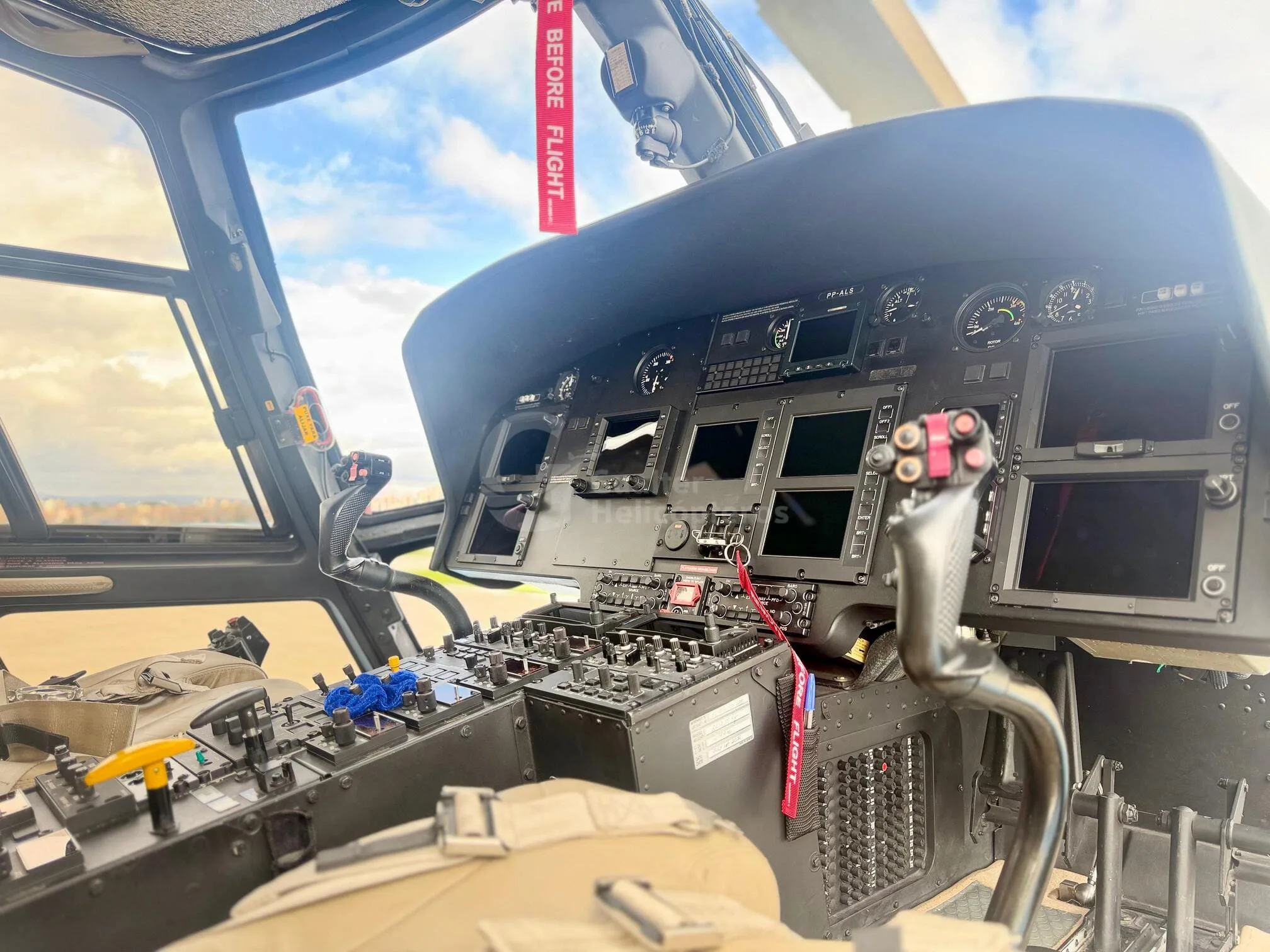 The cockpit of a helicopter showing the instrument panel, controls, and pilot's seat.