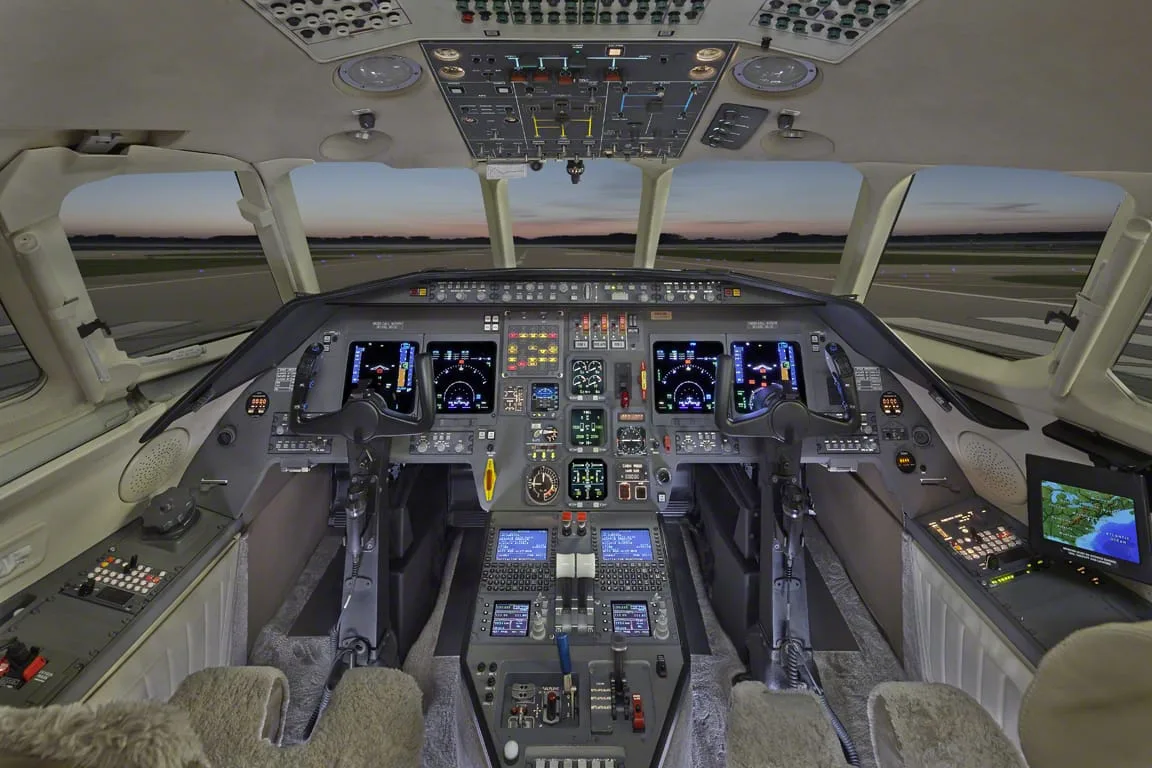 The cockpit of a business jet with multiple digital displays and controls.
