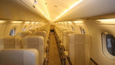 Interior view of an aircraft cabin with rows of beige seats.